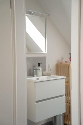 a white bathroom with a sink and a mirror at Altstadt Suite Bitburg in Bitburg