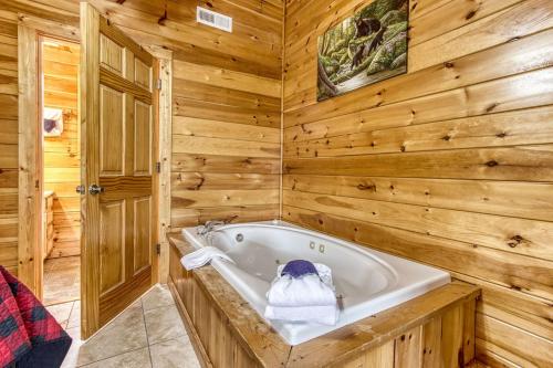 a bath tub in a room with wooden walls at Bucky's Bungalow, Free Attraction Tickets, Hot Tub, WIFI!!! in Gatlinburg