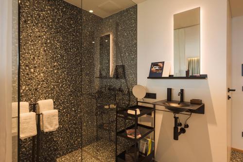 a bathroom with a shower with a sink and a mirror at Berghotel Predigstuhl in Bad Goisern
