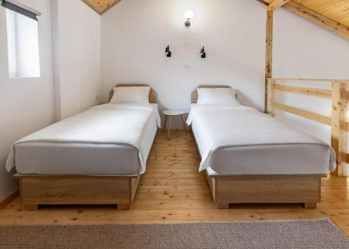two beds in a room with white walls and wooden floors at KING rooms in Bečej