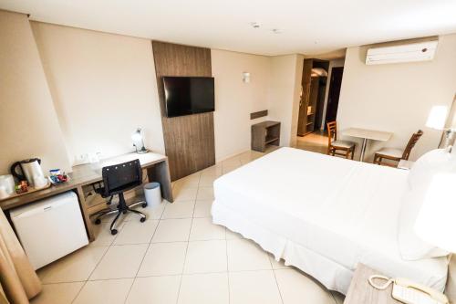 ein Hotelzimmer mit Bett, Schreibtisch und Fernseher in der Unterkunft Hotel Inter Cuiaba in Cuiabá