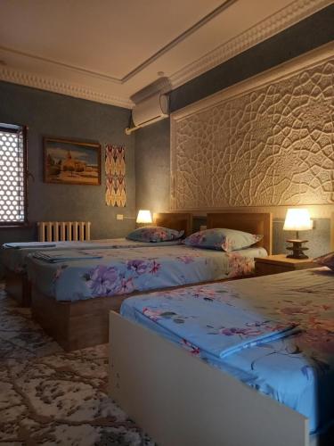 a hotel room with two beds and two lamps at LION Guest House in Bukhara
