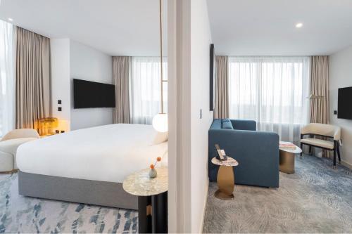 a hotel room with a large bed and a blue chair at Dorsett Hotel Canary Wharf in London