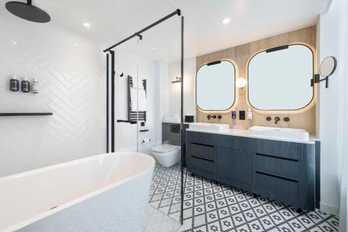 a bathroom with a tub and a sink and a toilet at Dorsett Hotel Canary Wharf in London