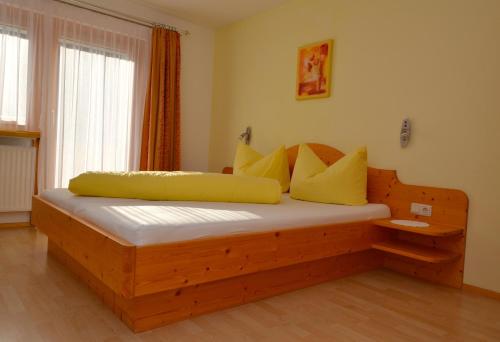 a bedroom with a wooden bed with yellow pillows at Pension Christine in Gaschurn