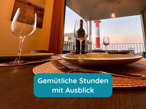 a table with two glasses and a bottle of wine at Meerglück am Beltblick Fehmarn - FeWo mit Sauna, Blick auf Ostsee und Leuchtturm, nur 150 m zum Meer in Fehmarn