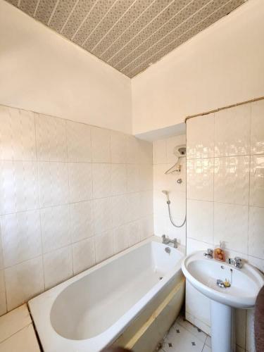 a white bathroom with a tub and a sink at S & J Lodge with high speed Starlink WiFi in Tamale