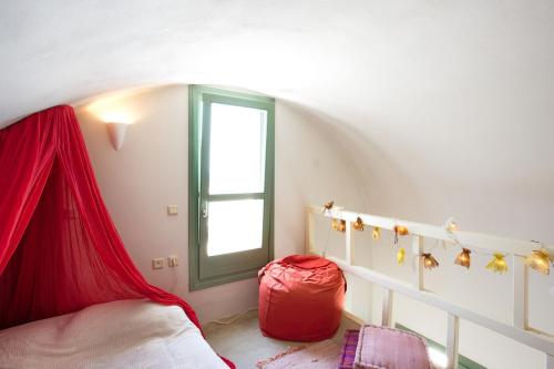 a bedroom with a bed with a red curtain and a window at Margarita Studio - Sunset View in Santorini