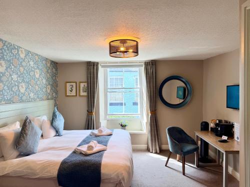 a bedroom with a bed and a desk and a window at The Queen's Head in Alnwick