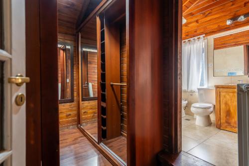 a bathroom with a toilet and a wooden wall at INDÓMITO HOSTEL in San Carlos de Bariloche