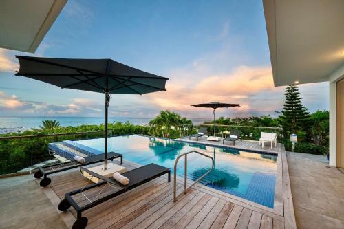 a swimming pool with chairs and an umbrella on a balcony at Skyline Villas - Villa Skyline with stunning Ocean View in Providenciales