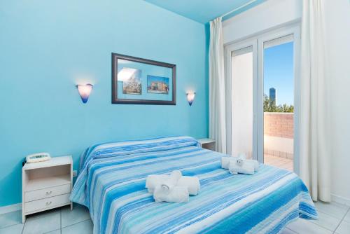 a blue bedroom with a bed with towels on it at Hotel Sogno in Cesenatico