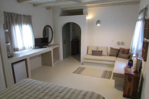 a white living room with a couch and a tv at Margarita Studio - Sunset View in Santorini