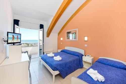 a bedroom with two beds and a balcony at Hotel Sogno in Cesenatico