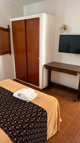 a room with a bed and a desk and a television at Hotel Pueblo Huarpe in San Luis