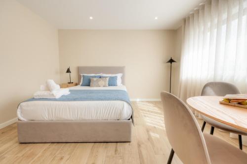 a bedroom with a bed and a table with chairs at Calvário Suites II in Chaves