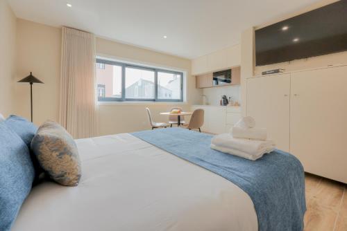a bedroom with a large white bed and a table at Calvário Suites II in Chaves