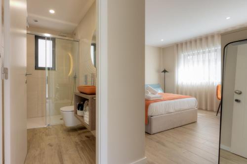 a bedroom with a bed and a bathroom with a shower at Calvário Suites l in Chaves