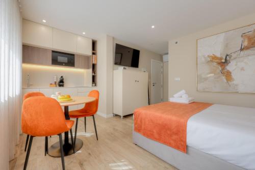 a bedroom with a bed and a table and chairs at Calvário Suites l in Chaves