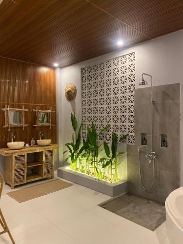 a bathroom with a shower and a plant at Oceanview Cottage Cempaga - entire 2 BR Bungalow 135 sqm in Temukus