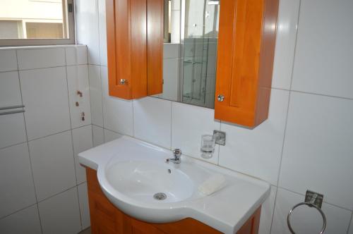 La salle de bains est pourvue d'un lavabo blanc et d'un miroir. dans l'établissement Elmina Bay Resort, à Elmina
