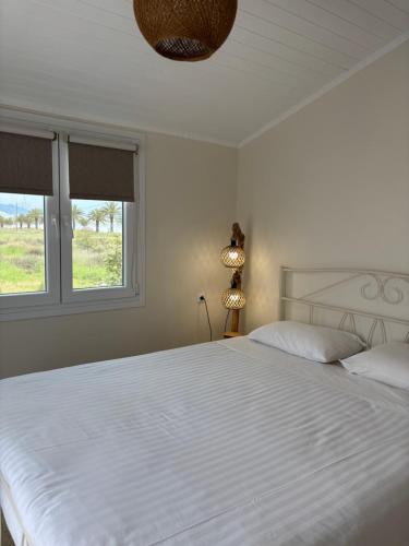 a bedroom with a large white bed with two windows at Sea View Residence in Nea Kios