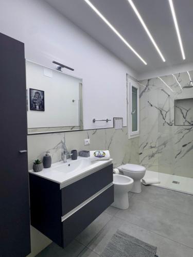 a white bathroom with a sink and a toilet at U Zu Ciccio in Terrasini
