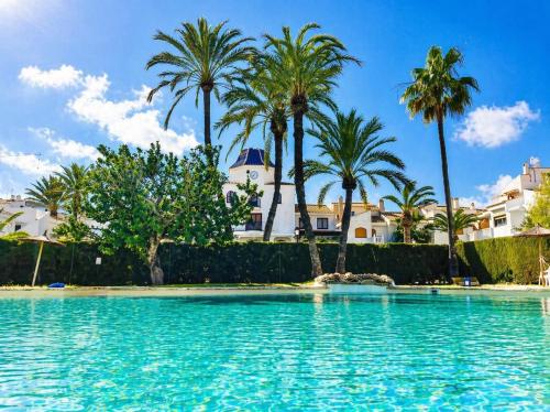 a swimming pool with palm trees in the background at Stay in Costa Hispania in Santa Pola