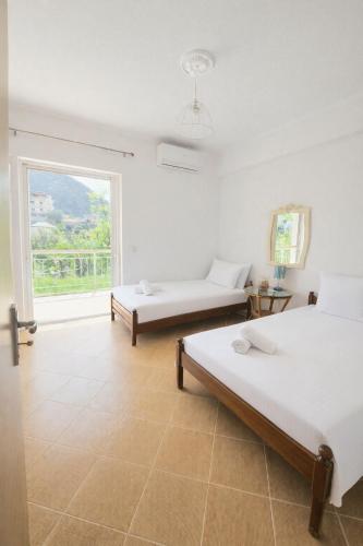 two beds in a room with a large window at Cozy Home in Delvinë