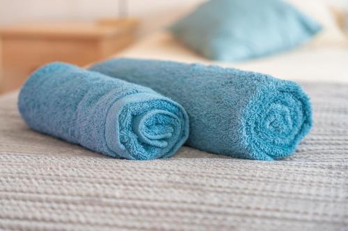 a blue rolled up towel on a bed at Baleal Bay Guesthouse in Baleal