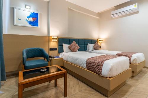 a hotel room with two beds and a chair at Hotel Altura CHHATRAL in Nandāsan