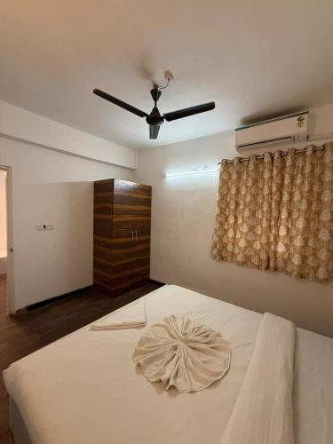 a bedroom with a white bed with a ceiling fan at Sunshine Park By RoomzAway in Candolim