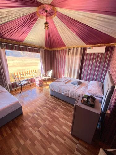 a tent bedroom with two beds and a table at Wadi Rum Lana luxury camp in Wadi Rum