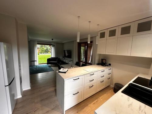 a kitchen with white cabinets and a living room at Domek nad jeziorem Kamionki Małe in Kamionki Małe