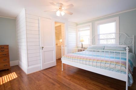 a white bedroom with a bed and a ceiling fan at Swamp Rabbit Inn TR in Travelers Rest