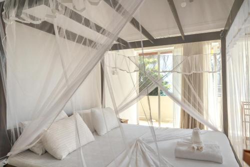 a bedroom with a white canopy bed with white pillows at Edelweiss Resort in Mirissa