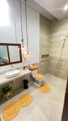 a bathroom with a sink and a toilet and a mirror at CASA TEMPORADA BARREIRINHAS Yellow 3 in Barreirinhas