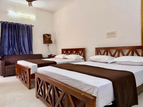 a hotel room with two beds and a couch at Nanasu Home stay in Malpe