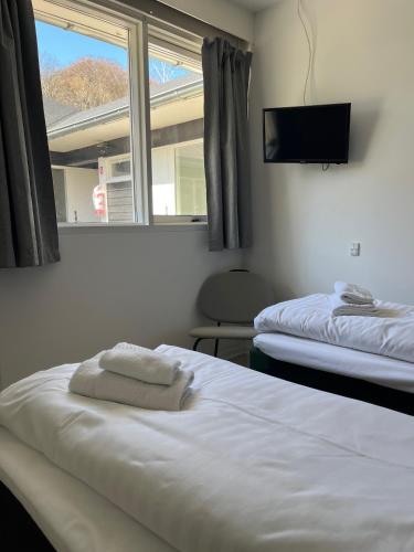 two beds in a room with a window and a tv at Hotel Færgelunden in Jægerspris