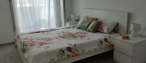 a bedroom with a bed with a floral comforter and a window at Apartman TUSUM Ražanac in Ražanac