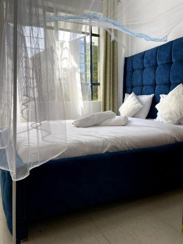 a bedroom with a blue bed with a canopy at Bay Loft 1 Br Netflix Lake Views, Starlink in Homa Bay