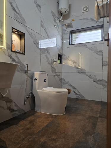 a bathroom with a white toilet and a window at Wanderlust Villas in Pinangode