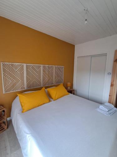 a bedroom with a large white bed with yellow pillows at Maison de jacque in Mimizan