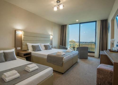 a hotel room with two beds and a large window at Hotel Magnific in Kranevo