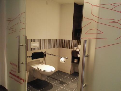 a bathroom with a toilet with red drawings on the wall at Allgäu Art Hotel in Kempten