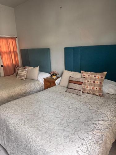a bedroom with two beds and a blue headboard at Hotel Casa 22 in San Miguel de Allende