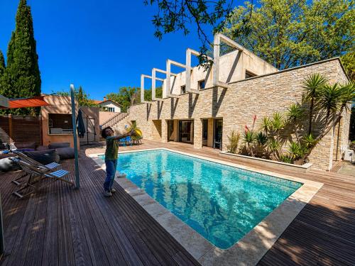 a young boy standing next to a swimming pool at Maison ROMIA in Fréjus