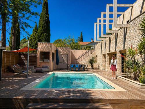 a woman is standing next to a swimming pool at Maison ROMIA in Fréjus