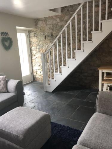 a living room with a staircase and a couch at 2, The Lodge, Tideswell in Tideswell