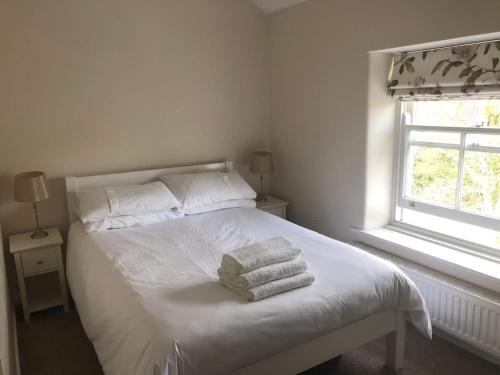a bedroom with a white bed with towels on it at 2, The Lodge, Tideswell in Tideswell